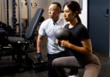 トレーナーの指導を受けながらトレーニングする男性