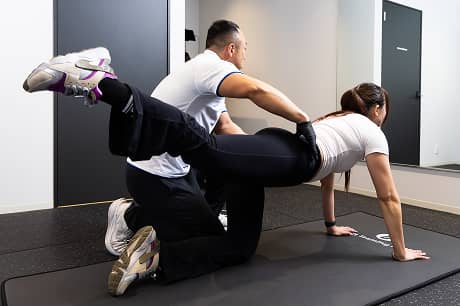 専属トレーナーとマンツーマンでトレーニングする女性